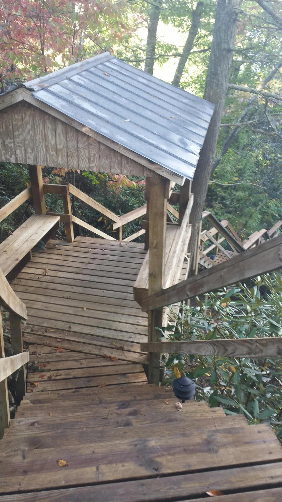 Metal roofed shelter over wooden steps on a wooded walkway — Skylight Repair & Installation work by our crew in Wellsburg