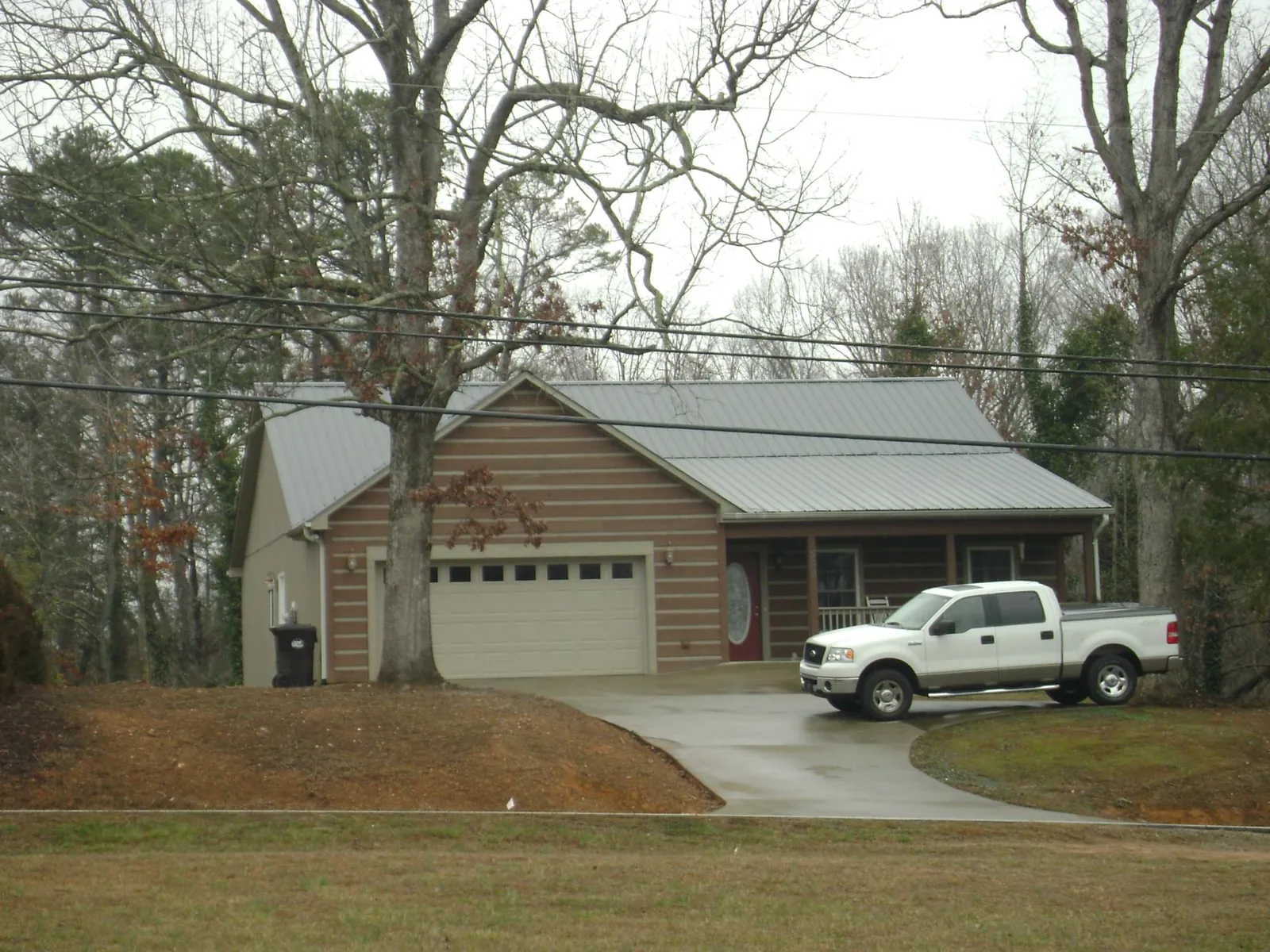 Gray metal roof on a log sided house with an attached two car garage in Wellsburg